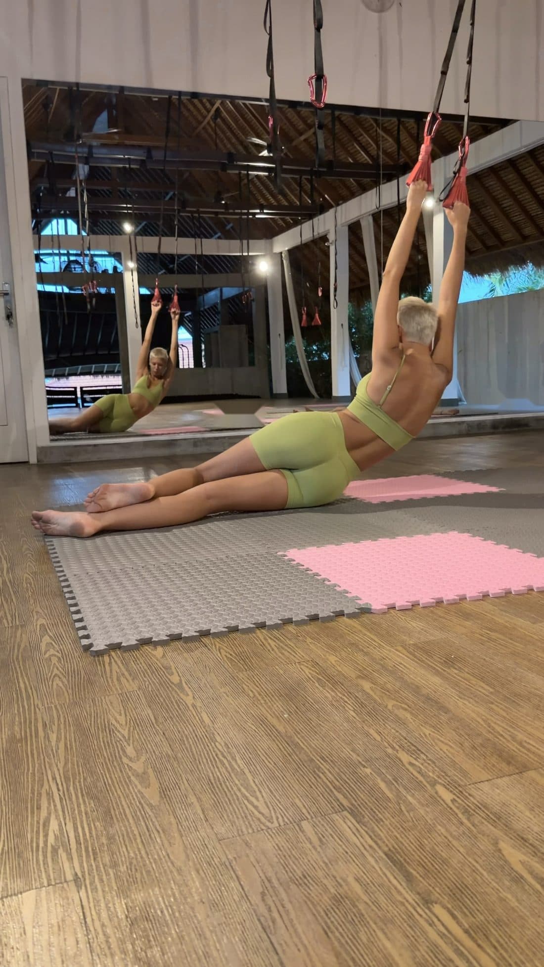 A woman stretches one side of her body holding a liana, the movement slow